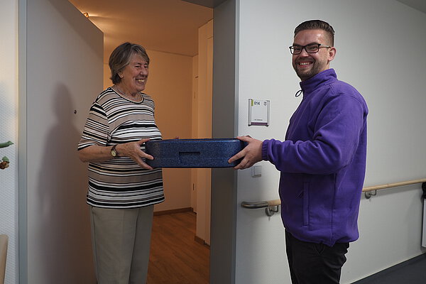 Mitarbeiter liefert Essen an Seniorin